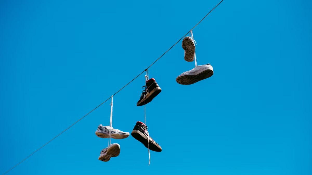 Shoes hanging on a line under a clear blue sky in Rimini, Italy.